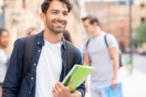 Portrait of a happy male student carrying his notebooks and smiling on the street - lifestyle concepts
